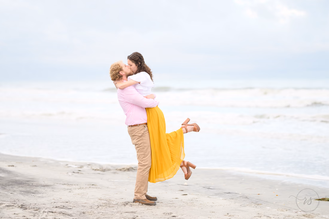 He lifts her into the air for a kiss on the beach - Huntington Beach State Park
