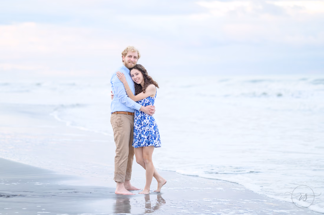 Couple hugging at the water's edge on an overcast day - Huntington Beach State Park