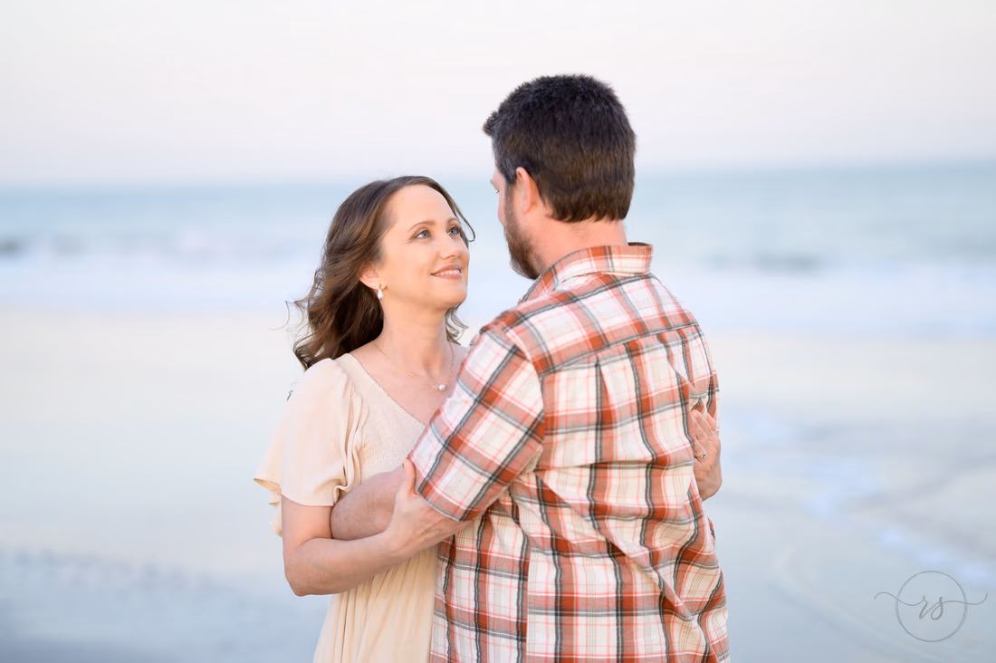 Couple hugging and smiling at each other by the water - Huntington Beach State Park