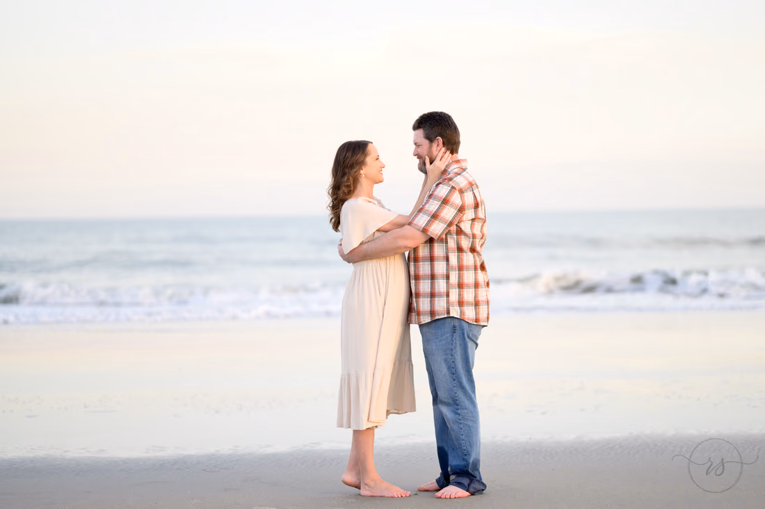 Couple standing close at the water's edge at sunset - Huntington Beach State Park