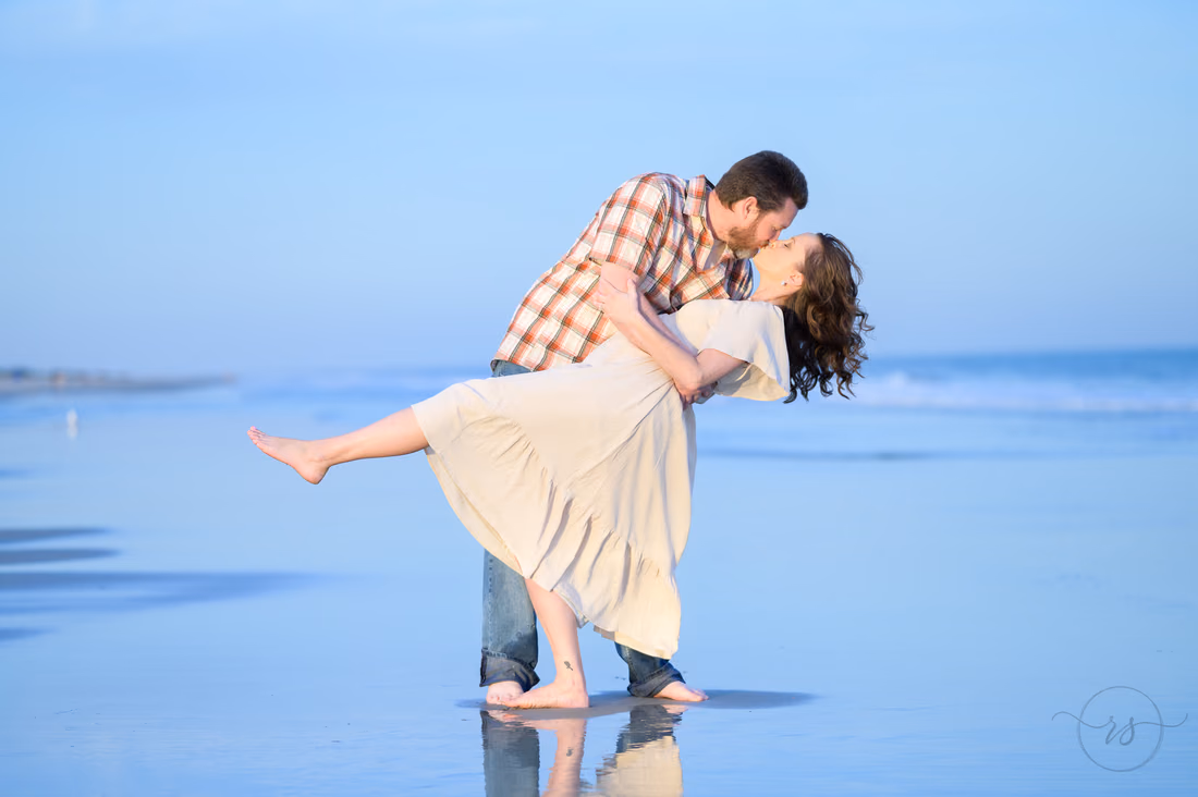 He dips her for a kiss in the shallow water - Huntington Beach State Park