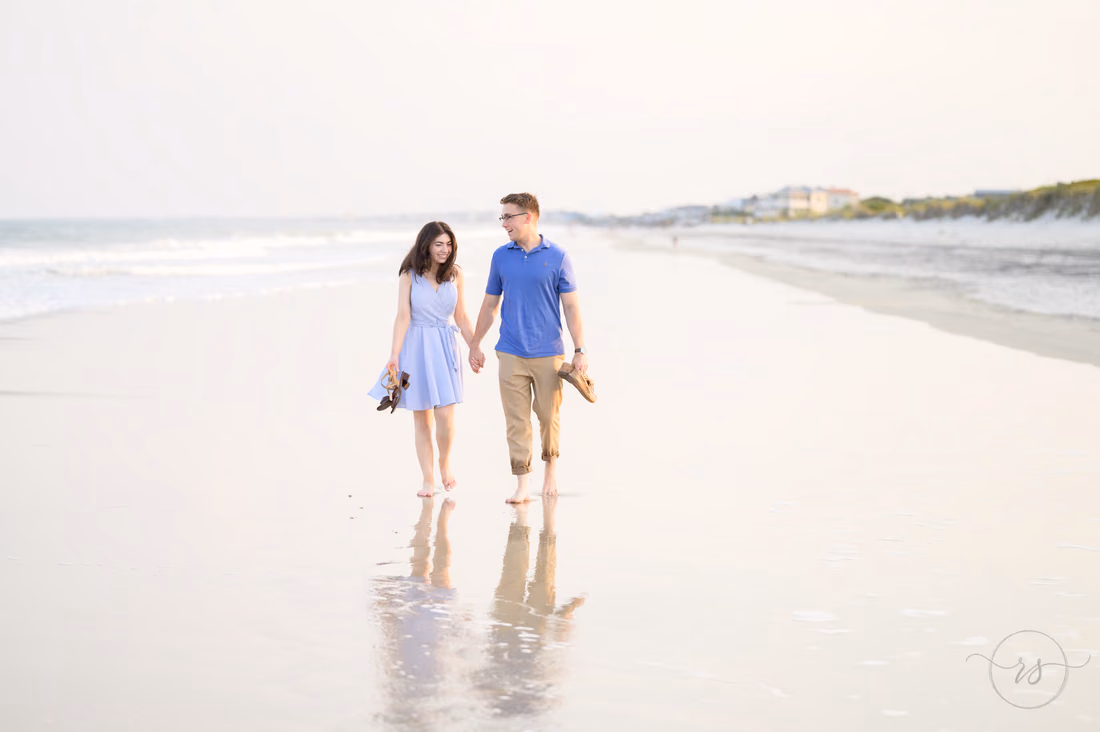 Couple walking hand in hand on the wet sand with their reflections - Huntington Beach State Park