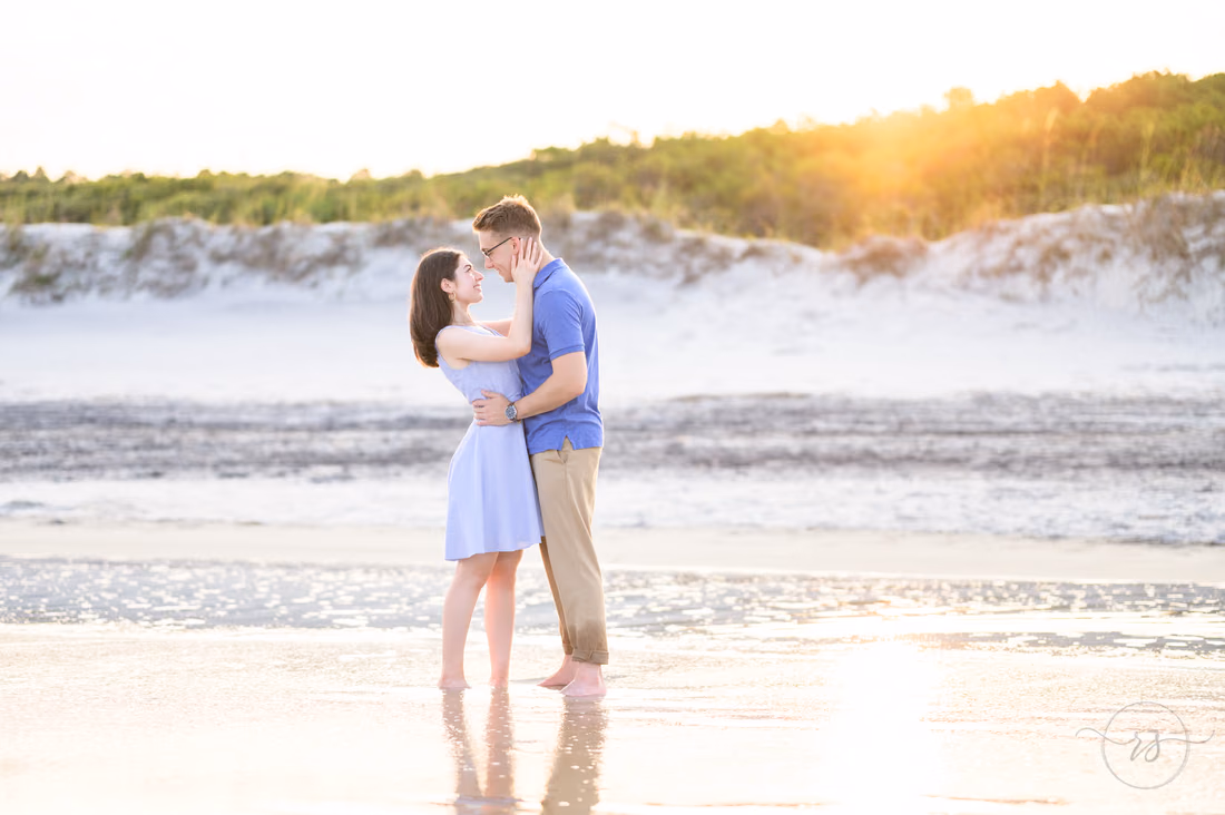 Couple hugging in the shallow water as the sun sets over the dunes - Huntington Beach State Park