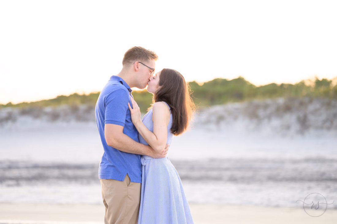 Couple kissing by the water with the sunset glow on the dunes - Huntington Beach State Park