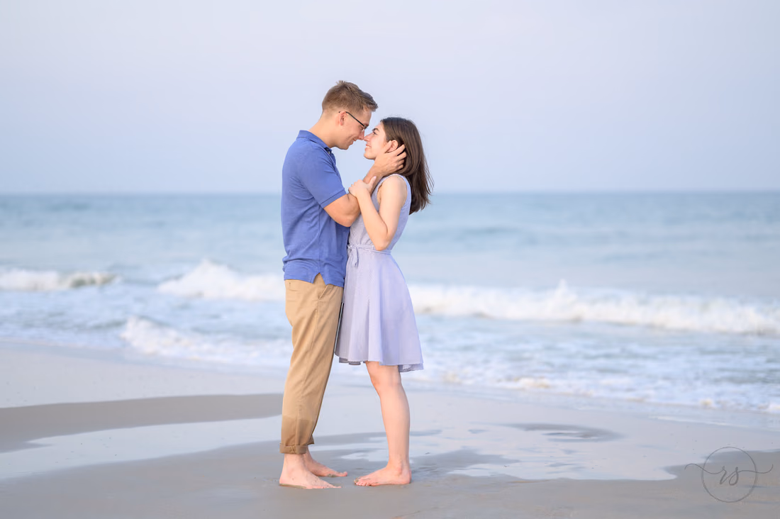 She holds his face as they stand barefoot by the waves - Huntington Beach State Park