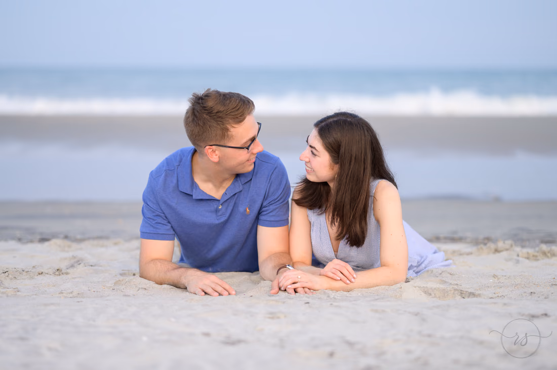 Couple lying on the sand smiling at each other - Huntington Beach State Park