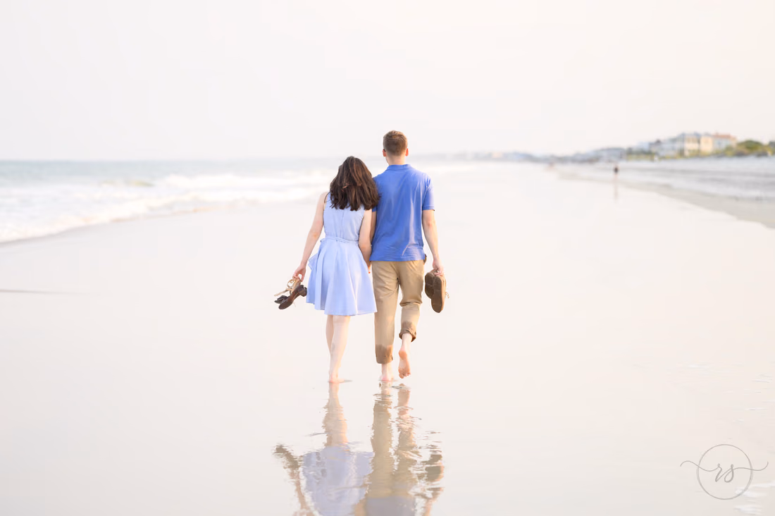 Couple walking away down the beach holding their shoes - Huntington Beach State Park