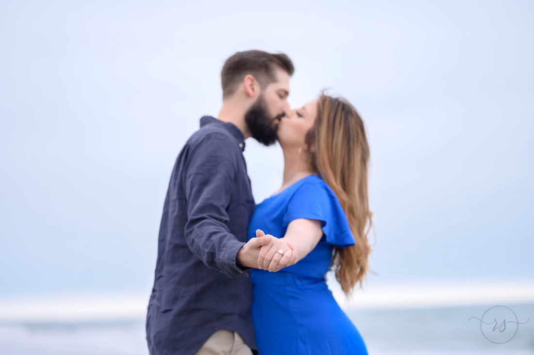 Couple kissing and holding hands in a dance pose by the ocean - Huntington Beach State Park