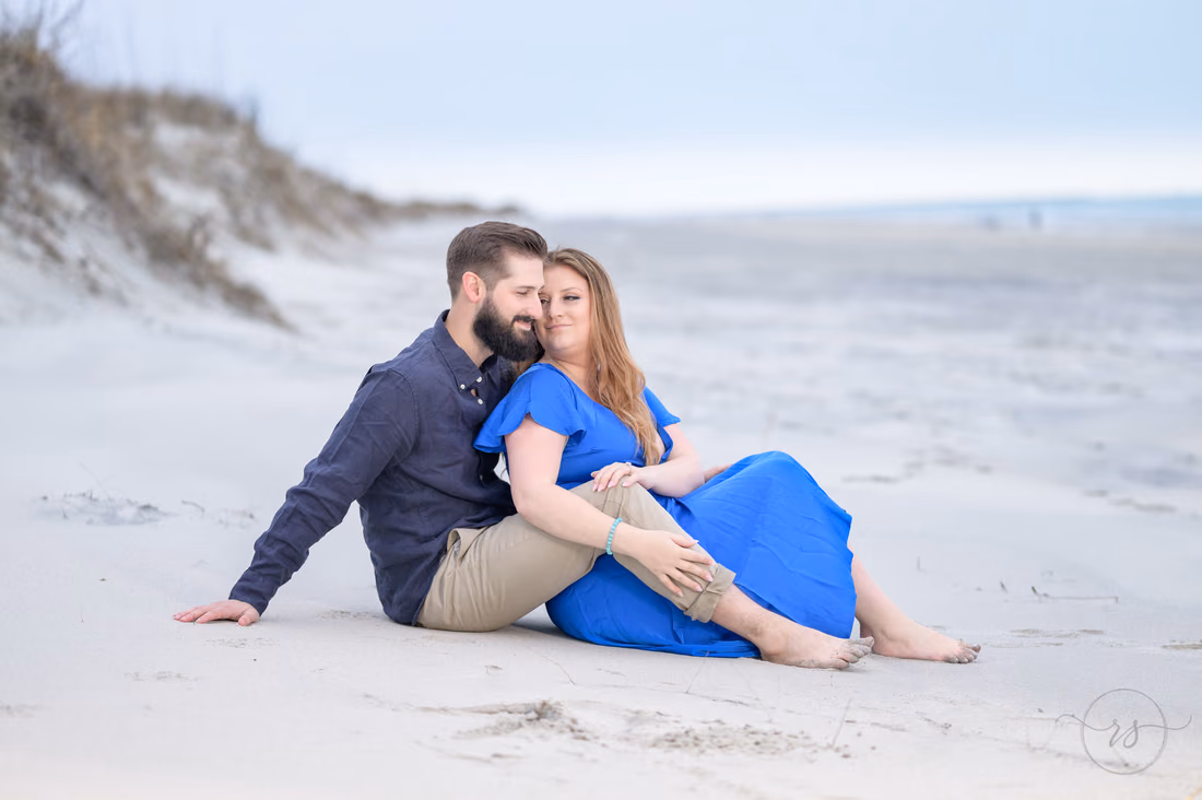 Couple sitting together on the sand by the dunes - Huntington Beach State Park