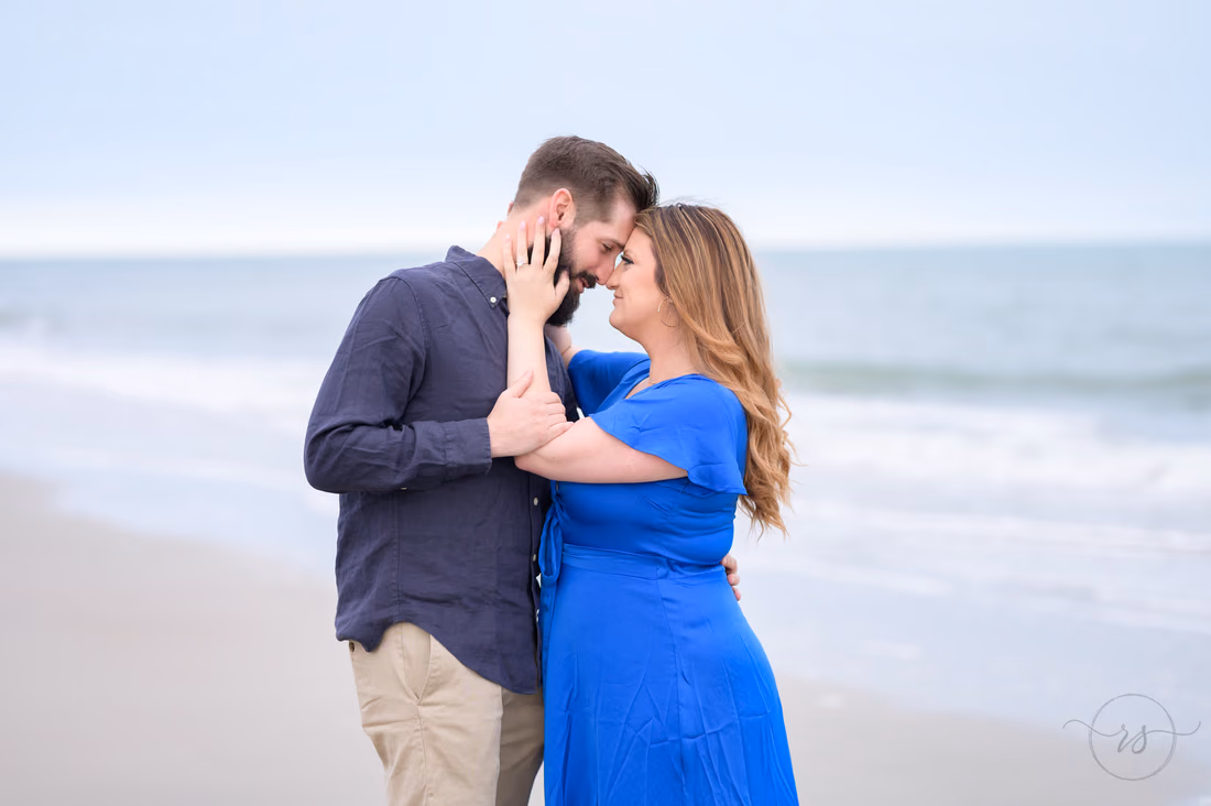 Couple forehead to forehead on the beach on a cloudy day - Huntington Beach State Park