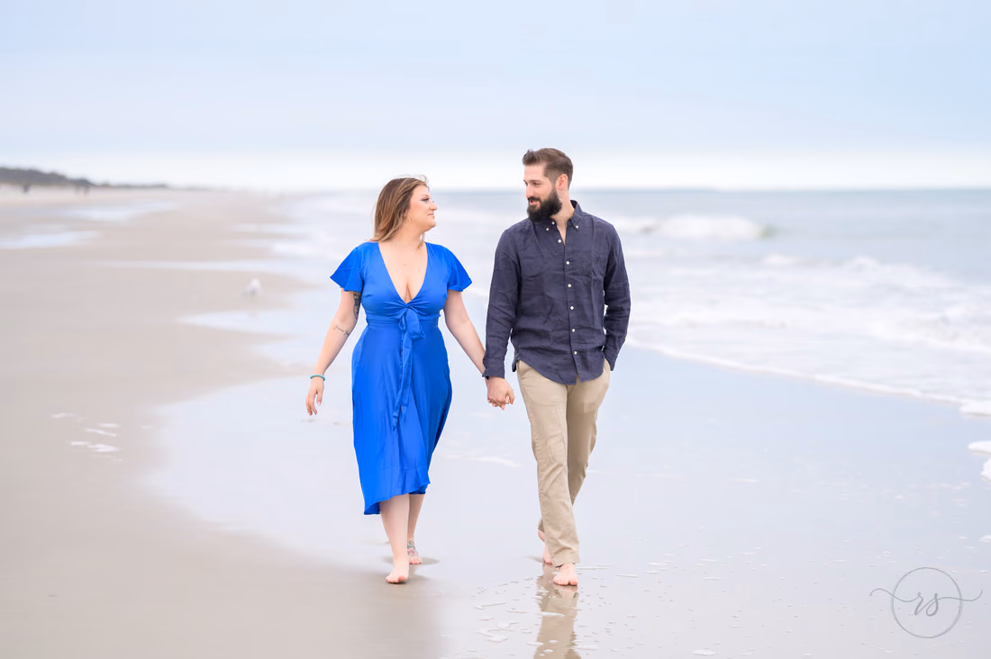 Couple walking hand in hand along the shoreline - Huntington Beach State Park