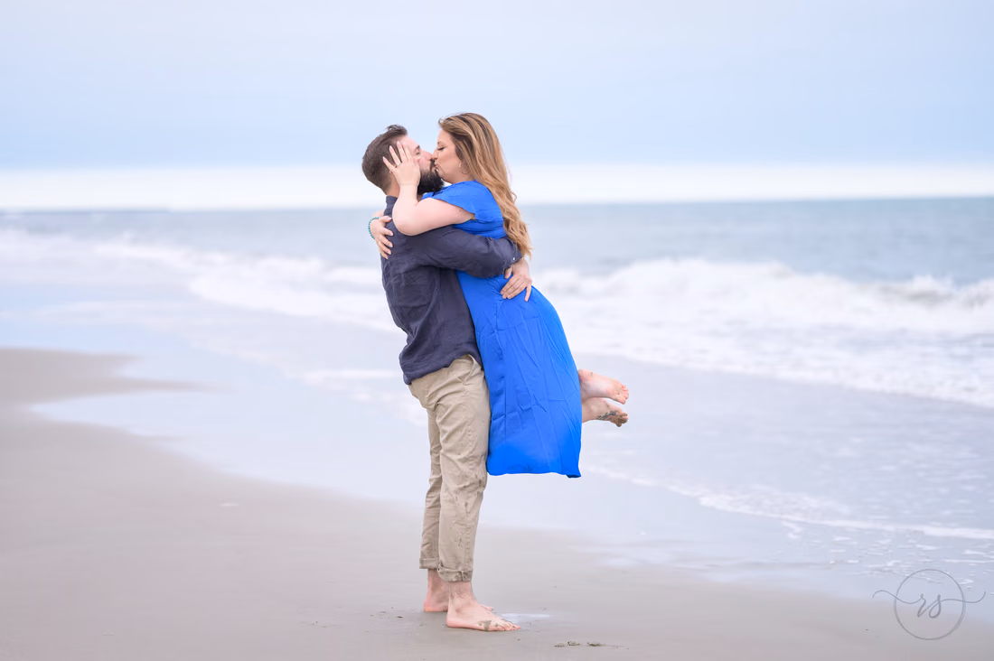He lifts her off her feet for a kiss by the waves - Huntington Beach State Park