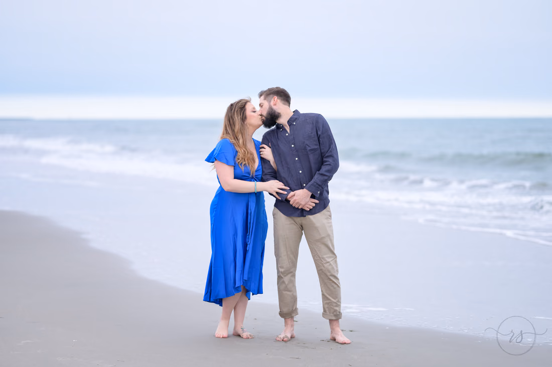 Couple kissing at the water's edge on a cloudy day - Huntington Beach State Park