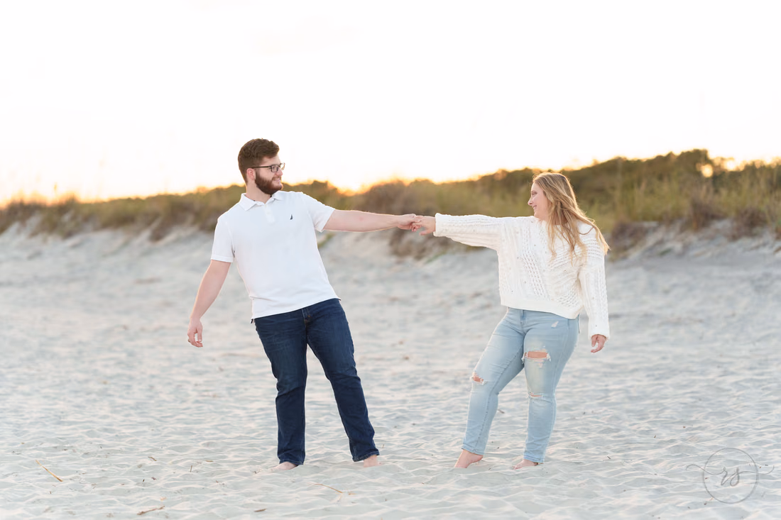 He twirls her on the sand in front of the dunes - Huntington Beach State Park