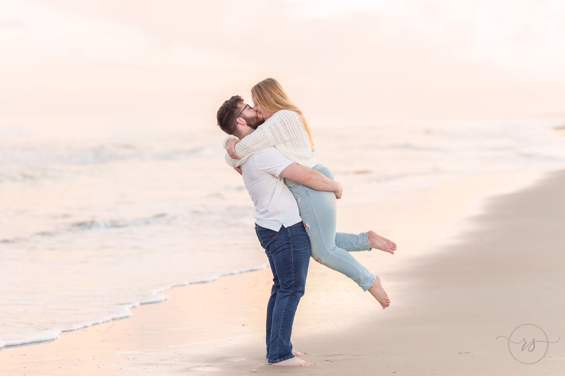 She jumps into his arms for a kiss by the water - Huntington Beach State Park