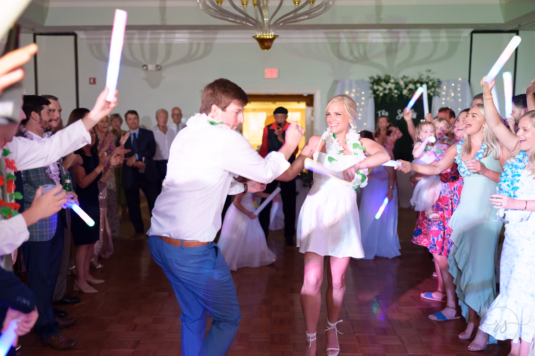Bride and groom dance with light-up foam sticks in the middle of the crowd at Pawleys Plantation