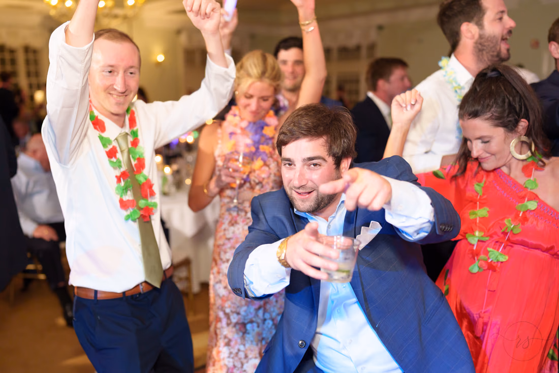 Guests in leis dance and point at the camera at Pawleys Plantation