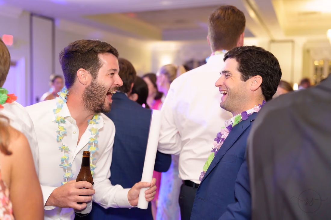 Guests in leis laugh with light-up foam sticks on the dance floor at Pawleys Plantation