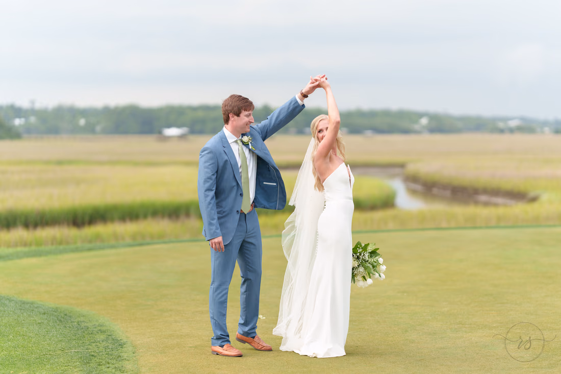 Groom twirls the bride on the golf course overlooking the marsh at Pawleys Plantation
