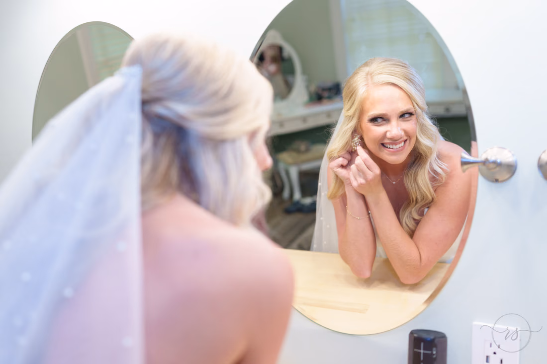 Bride putting earring on in mirror - Pawleys Plantation