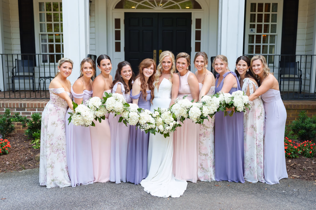 Bridesmaids lean in around the bride holding their bouquets out at Pawleys Plantation