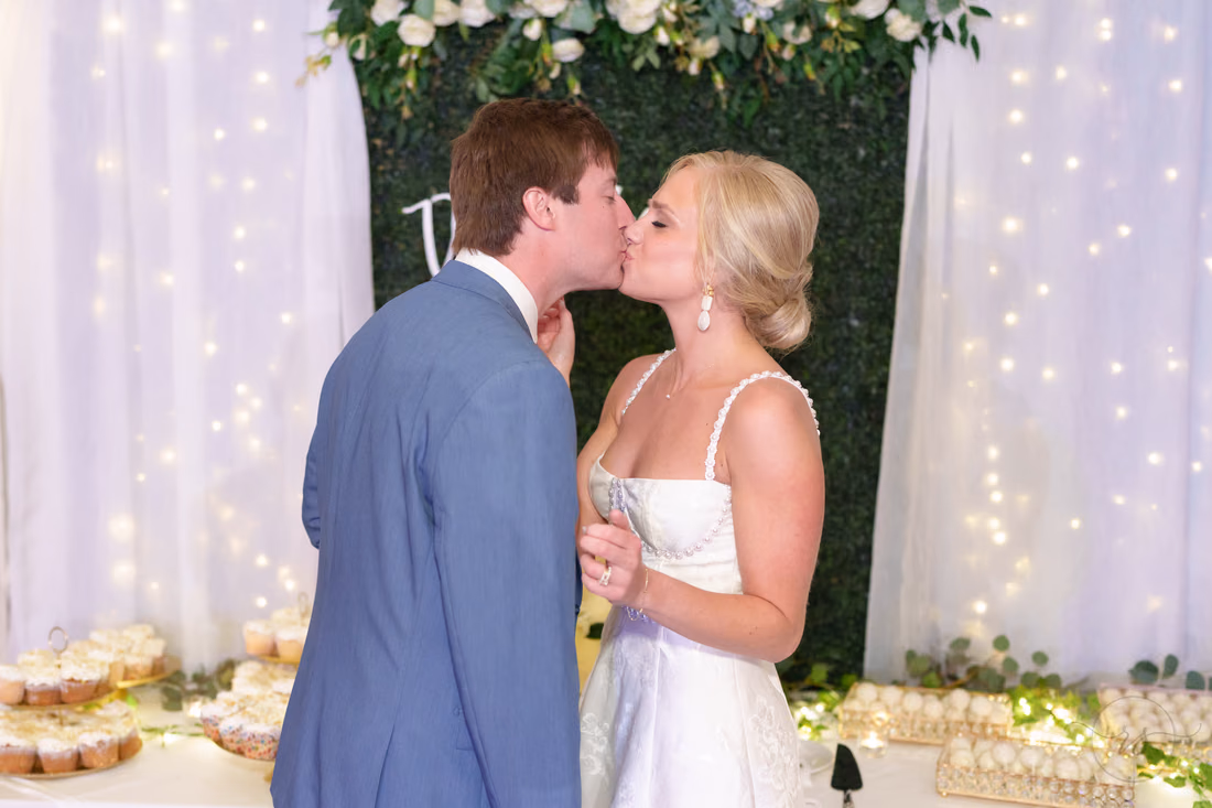 Bride and groom kiss beside the cake table at Pawleys Plantation