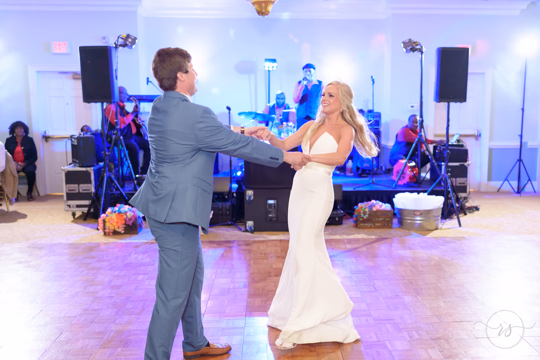 Bride laughs as the groom leads her across the dance floor at Pawleys Plantation