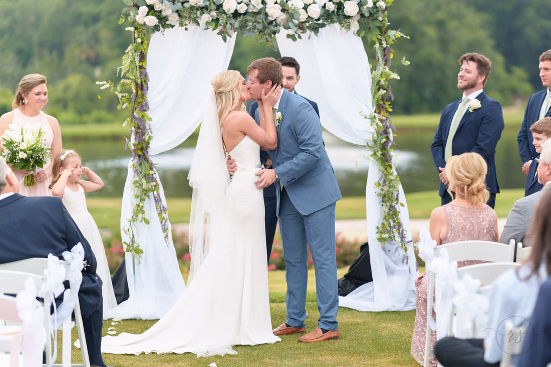 First kiss under the floral arch on the ceremony lawn at Pawleys Plantation