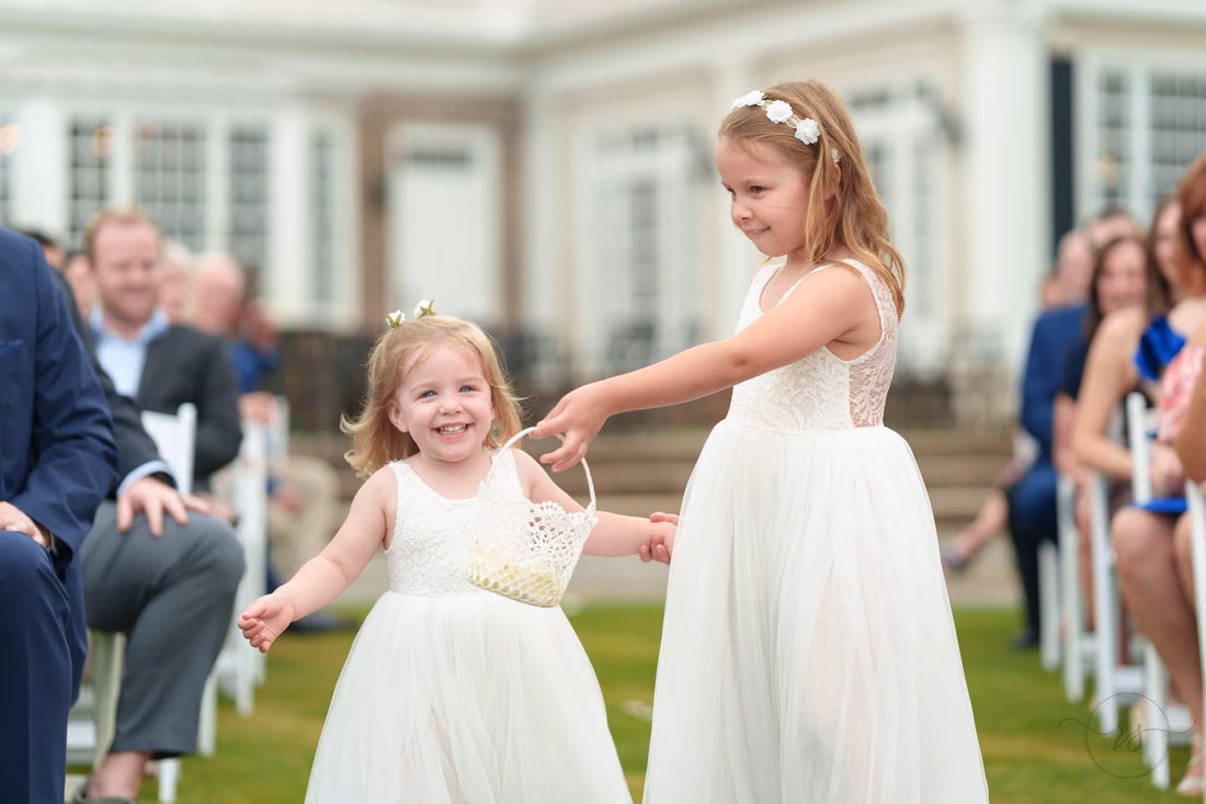 Flower girl tosses petals as the younger one smiles in the aisle at Pawleys Plantation