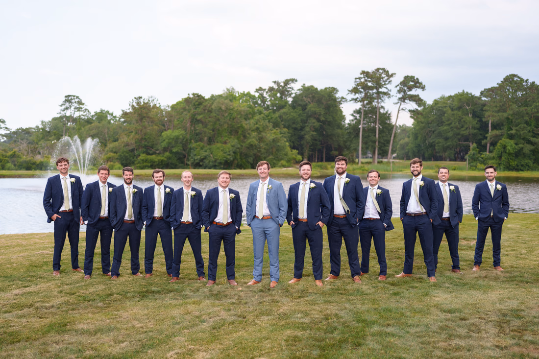 Groom and his twelve groomsmen in navy suits by the fountain pond at Pawleys Plantation