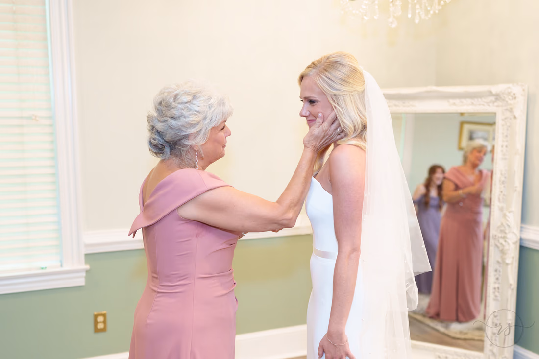 Mom holds the bride's face as they smile at each other at Pawleys Plantation