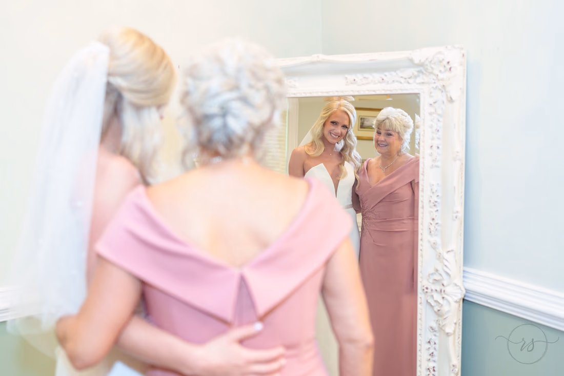 Bride and her mom hug and smile into the mirror at Pawleys Plantation