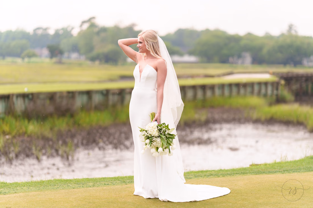 Bride poses with a hand in her hair beside the marsh at Pawleys Plantation
