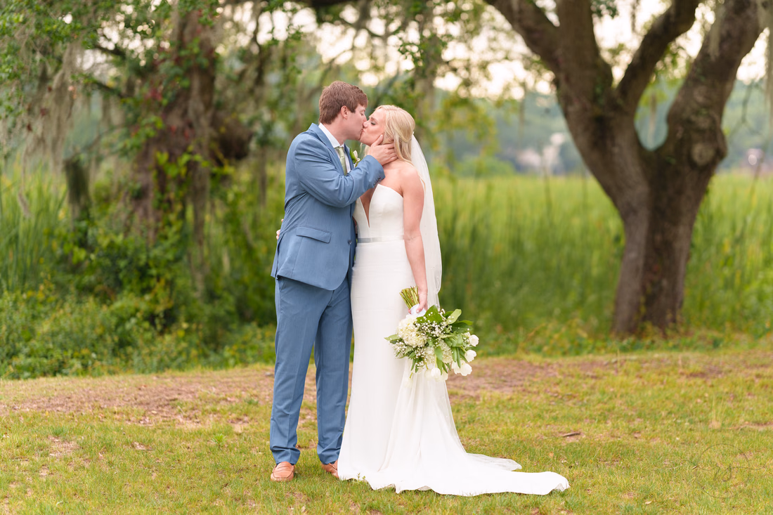 Groom kisses the bride's cheek under the mossy oaks at Pawleys Plantation