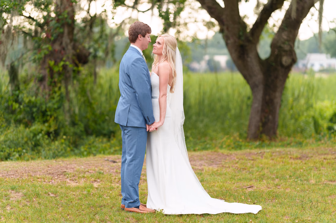 Bride and groom hold hands and gaze at each other under the oaks at Pawleys Plantation