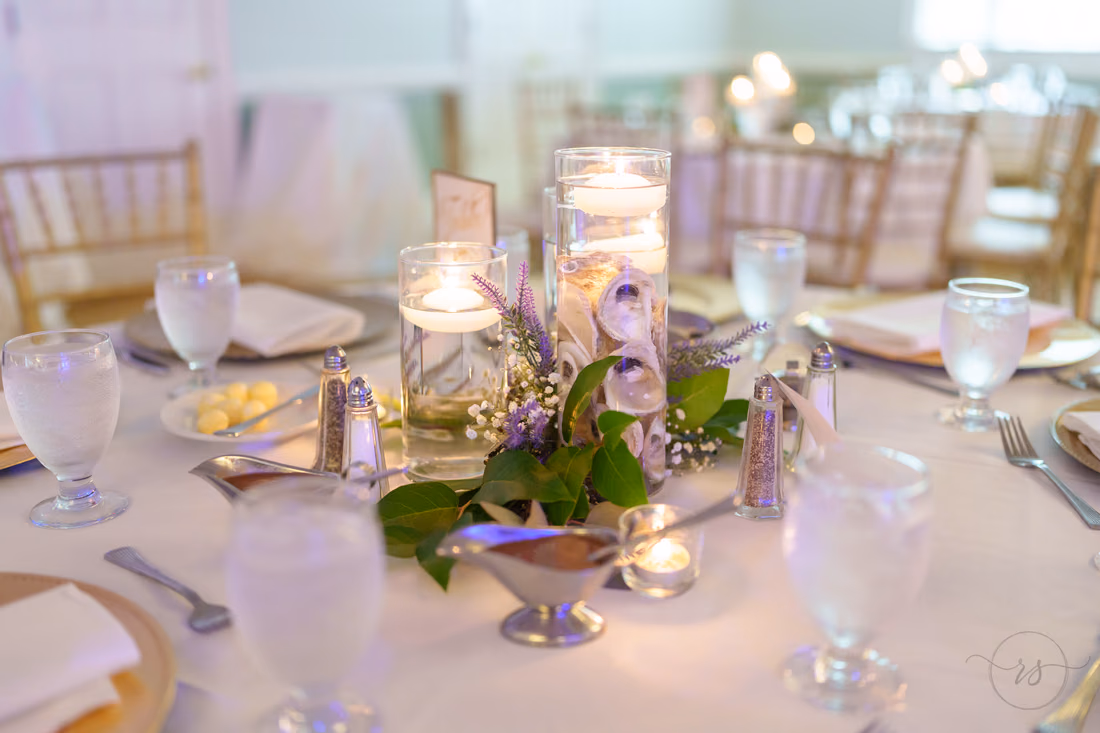 Floating candle centerpiece with lavender and greenery on a reception table at Pawleys Plantation
