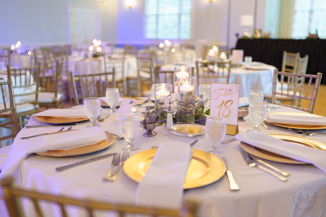 Reception table with gold chargers and a table number card at Pawleys Plantation