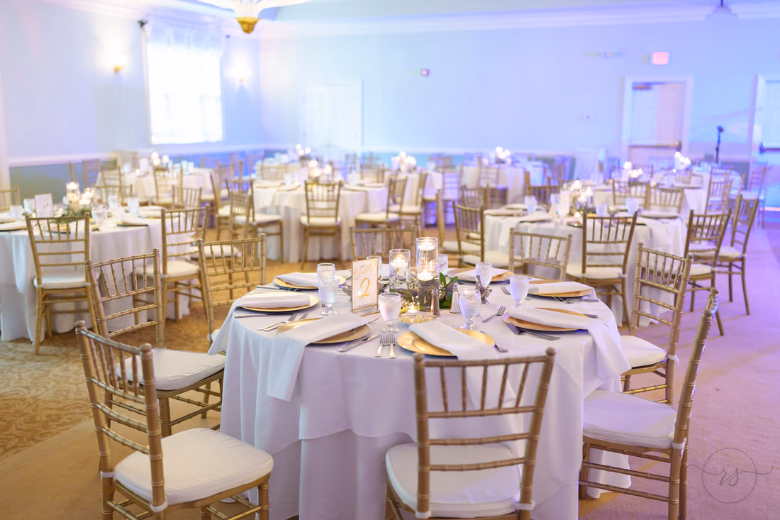 Ballroom set with round tables and gold chiavari chairs for the reception at Pawleys Plantation