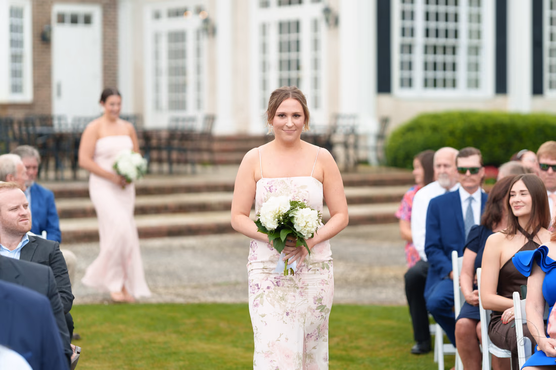 Bridesmaid in a floral dress walks down the aisle at Pawleys Plantation