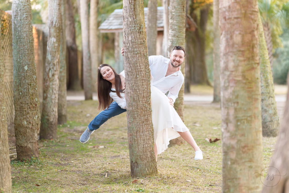 Couple peeking around the palm trees - Huntington Beach State Park