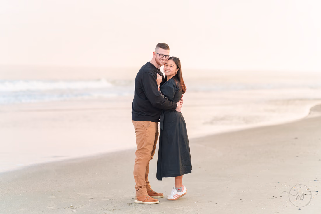 Couple hugging and smiling by the water at sunset - Garden City Beach