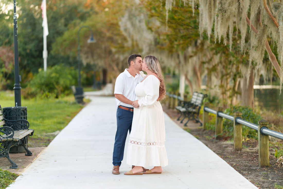 Couple kissing on the tree-lined riverwalk path by the benches - Conway Riverwalk