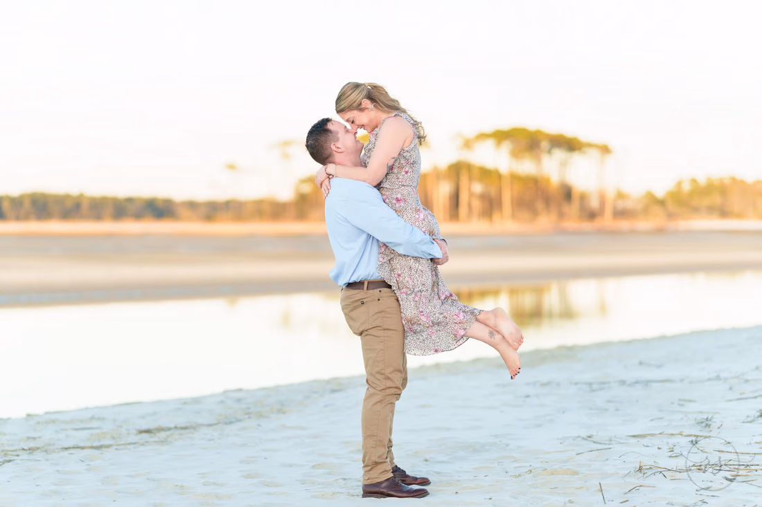 He lifts her for a kiss by the water - Cherry Grove Point