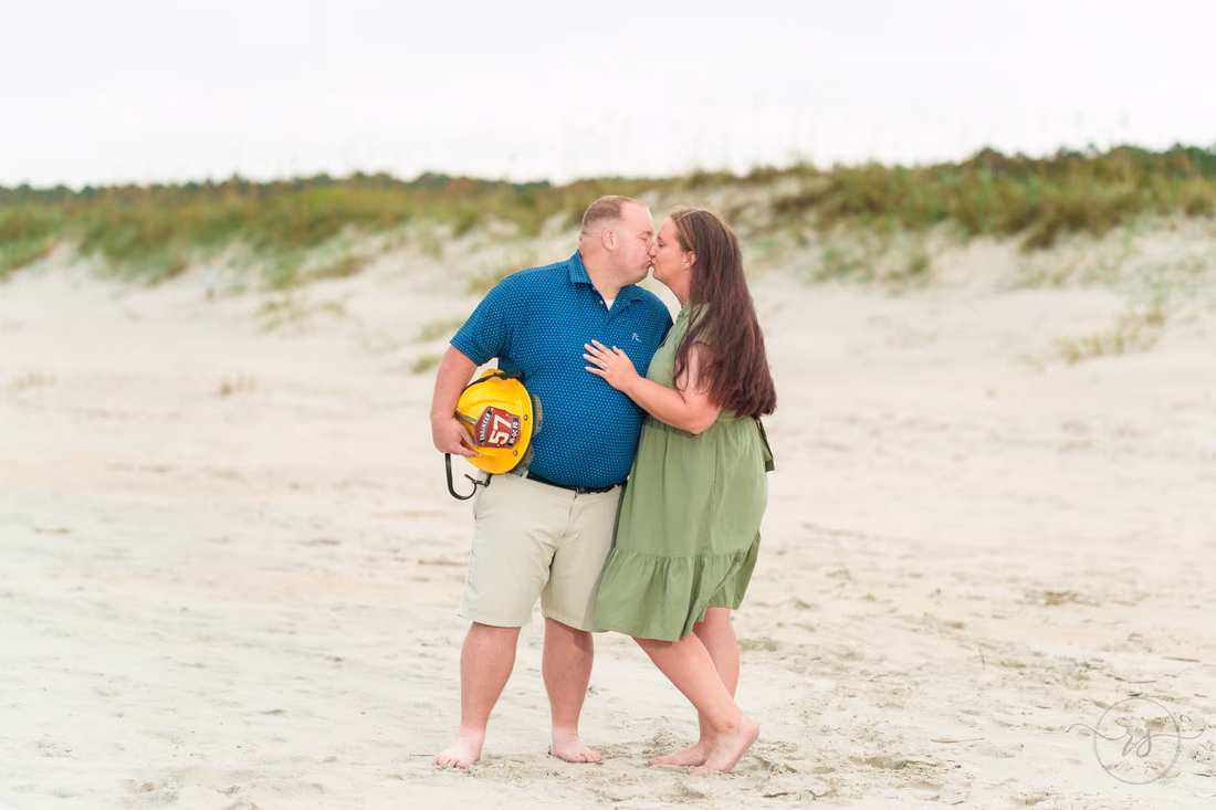 Couple kissing as he holds his firefighter helmet - Huntington Beach State Park