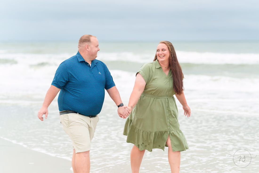 Couple laughing hand in hand along the shoreline - Huntington Beach State Park