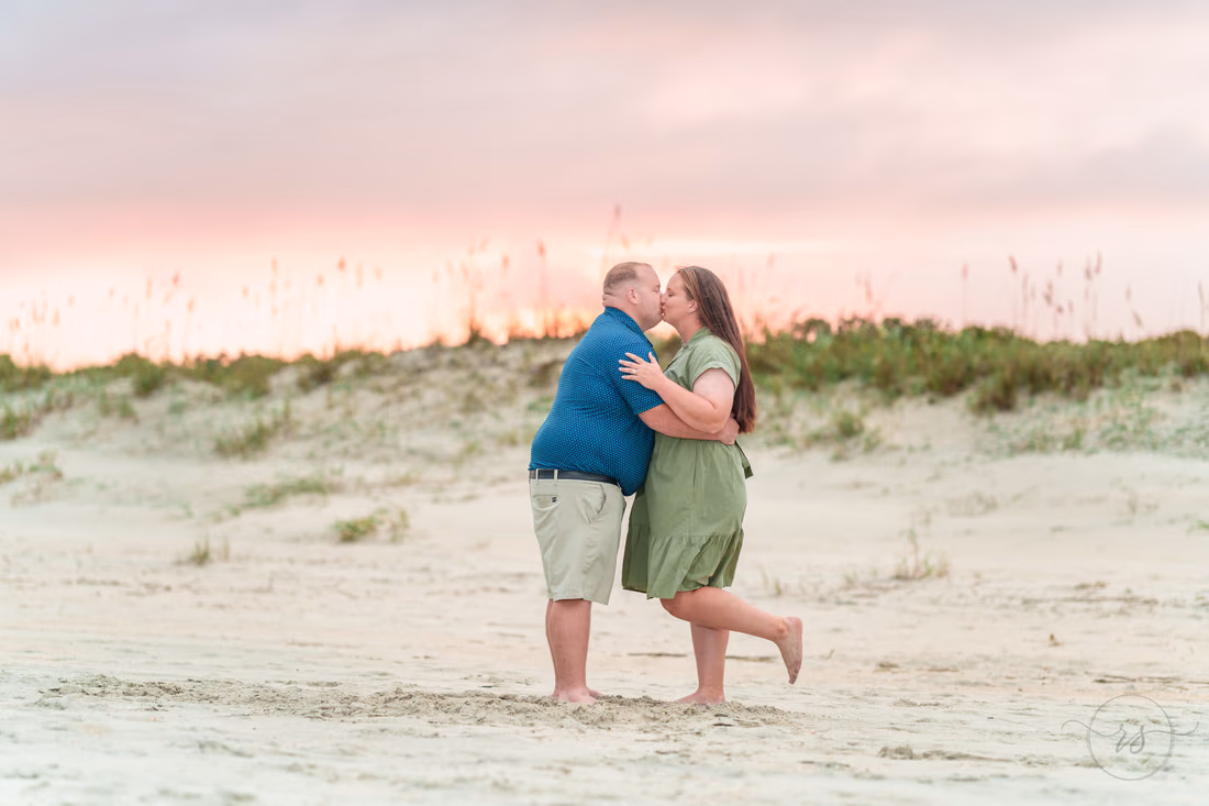 Couple kissing by the dunes under a pink sunset sky - Huntington Beach State Park