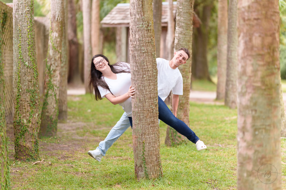 Couple peeking around the palm trunks - Huntington Beach State Park