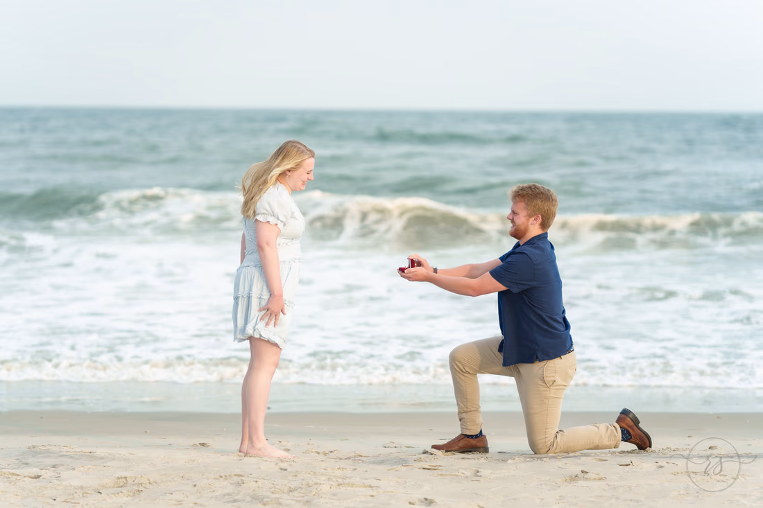 Man on one knee showing her the ring by the ocean - Huntington Beach State Park