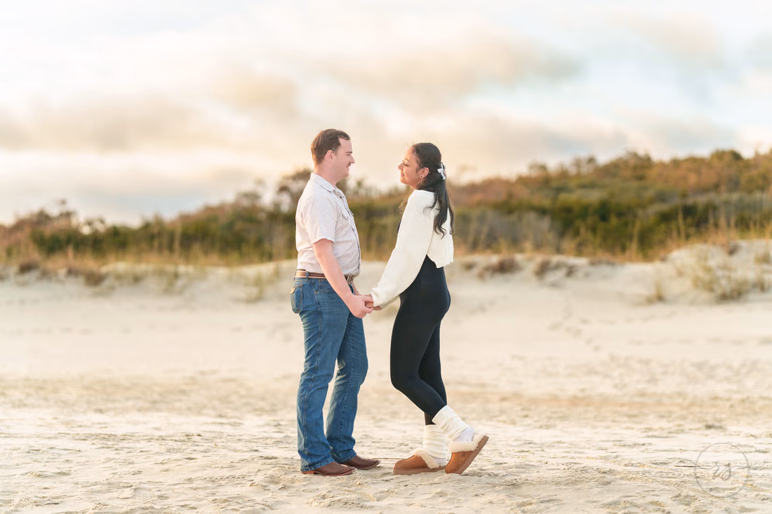 Couple holding hands in front of the dunes - Huntington Beach State Park