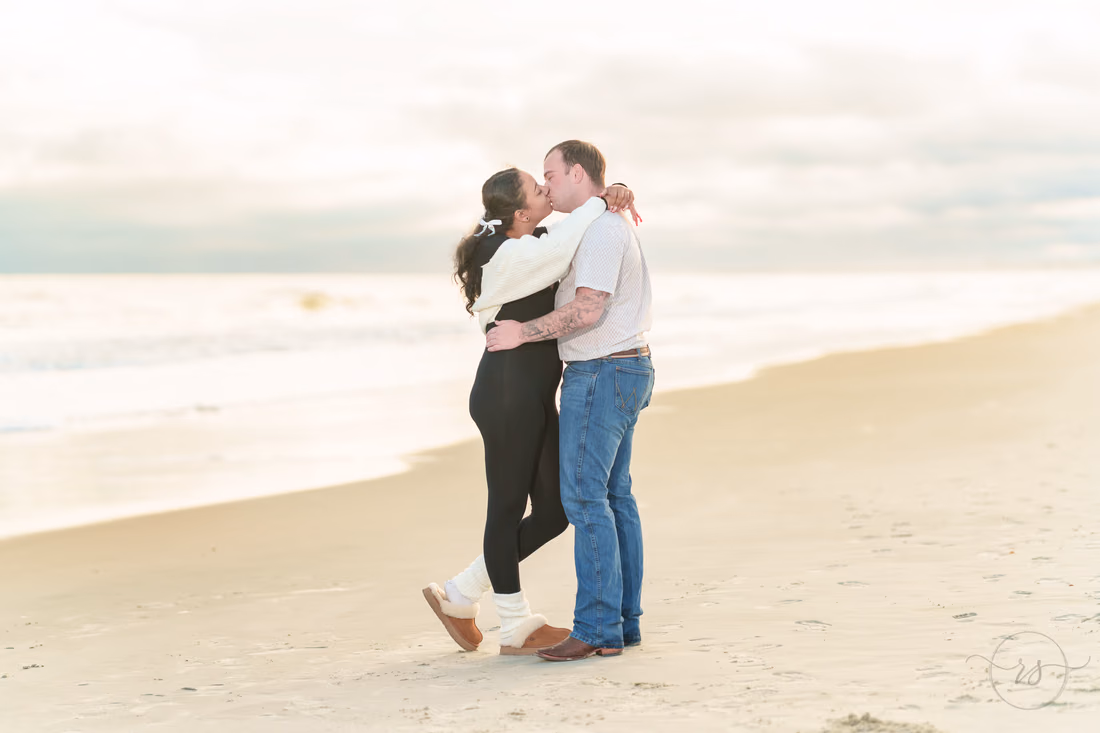 Couple kissing at the water's edge on an overcast day - Huntington Beach State Park